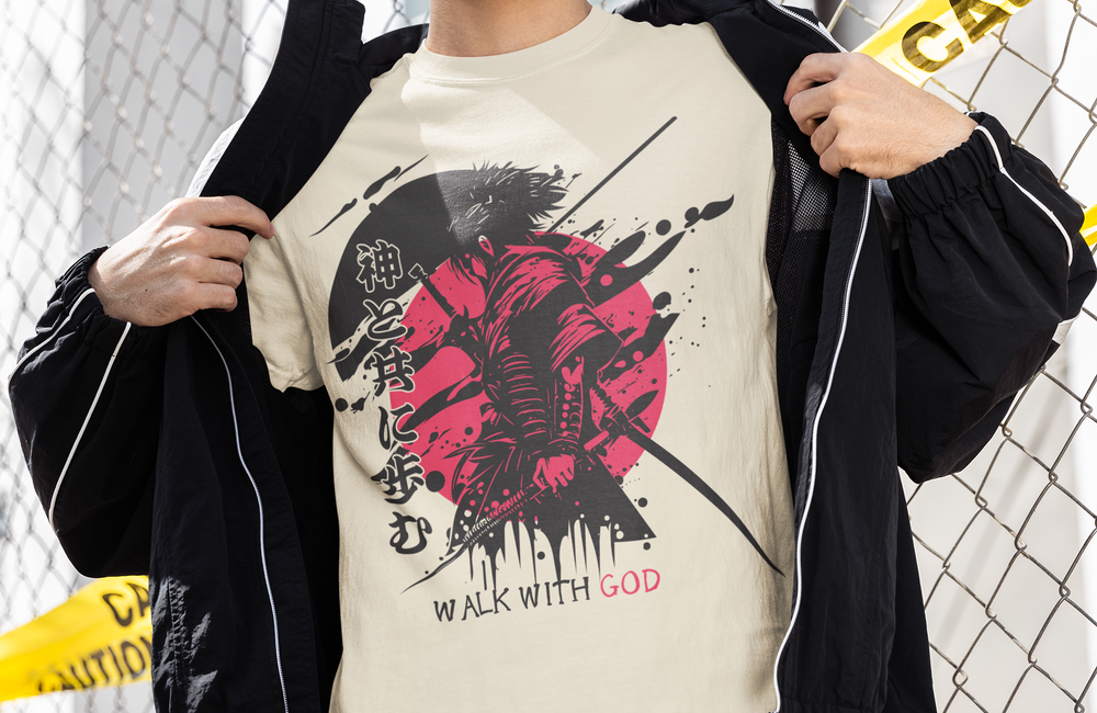 A man wearing a cream graphic t-shirt with a red and black design and the text 'WALK WITH GOD', styled with a black zip-up hoodie and sunglasses, standing in front of a chain-link fence with yellow caution tape.